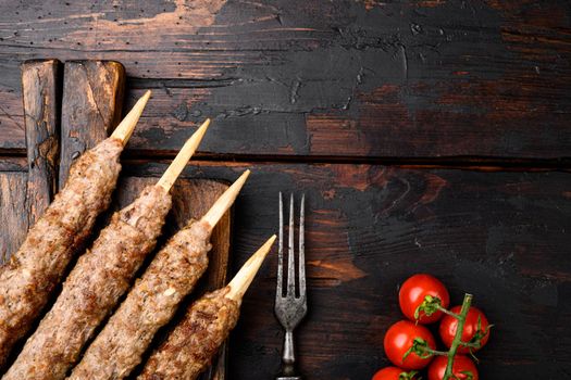 Shish kebab on a stick, from ground land mutton meat, on serving board, on old dark wooden table background, top view flat lay, with copy space for text