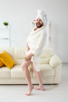 Funny bearded man wear turban towel makes himself a massage with massage brush. Male skin care and spa concept.