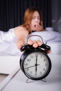 woman sleeping and wake up to turn off the alarm clock in morning