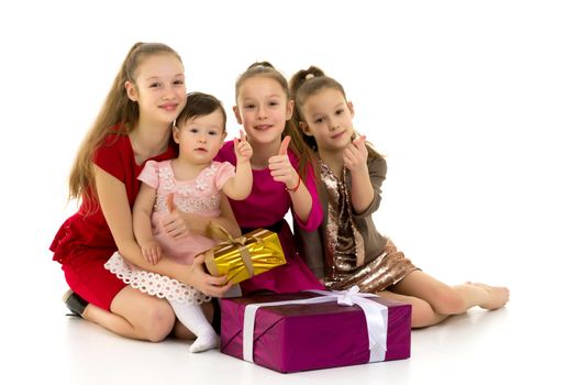Different age girls are sitting on the floor near gifts. Isolated over white background.