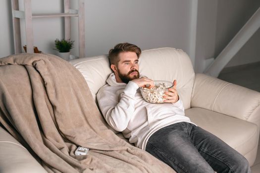 Man watching movies lying on a couch at home.