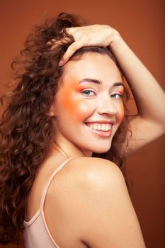 young pretty girl with blond curly hair posing cheerful on brown background, lifestyle people concept close up