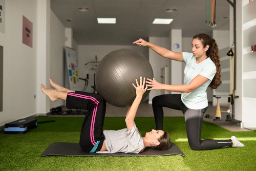 Physical therapist assisting young caucasian woman with exercise
