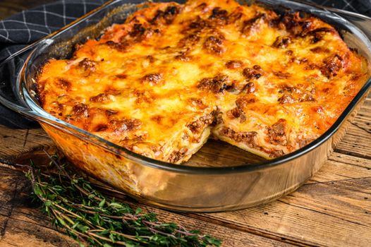 Lasagna with bolognese sauce and mince beef in a baking dish. Wooden background. Top view