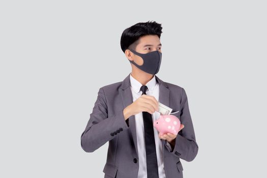 Young asian businessman in face mask holding money dollar and piggy bank isolated on white background, crisis of economic, business man in mask investment finance and saving during disease covid-19.