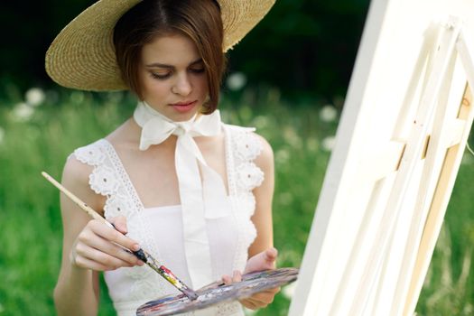 woman artist draws a picture on an easel outdoors