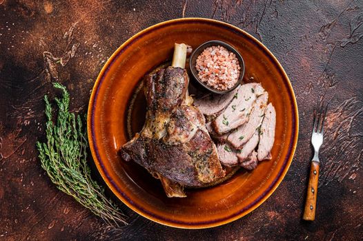 BBQ Roast Lamb mutton leg sliced on a rustic plate. Dark background. Top view