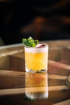 Yellow whisky sour cocktail garnished with mint