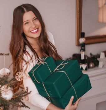Christmas holiday and sustainable gifts concept. Happy smiling woman holding wrapped presents with eco-friendly green wrapping paper