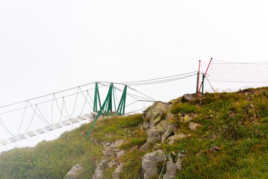 The empty rope bridge over the cliff on foggy day
