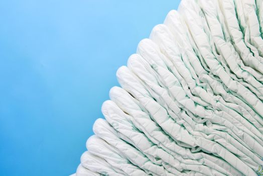 stack of baby diaper on blue background with copy space