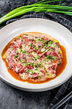 beef carpaccio with fresh green onions. Black background. Top view