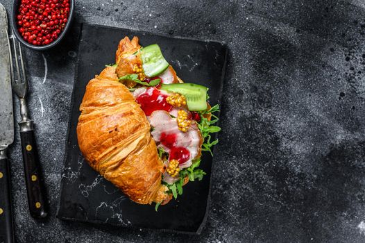 Croissant sandwich with cheese, arugula and ham. Black background. Top view. Copy space