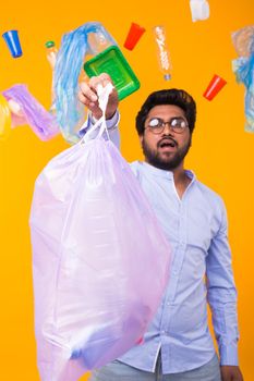 Plastic recycling problem, ecology and environmental disaster concept - Indian man holding garbage bag on yellow background