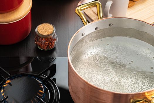 Copper pot with boiling water on a gas stove
