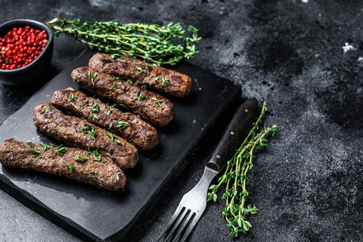 Grilled Shish kebab meat sausages. Black background. Top view. Copy space