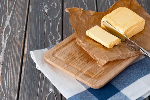 Wooden board with butter on blue checkered napkin