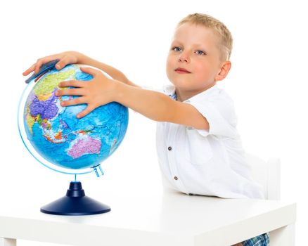 A little boy is studying geography on a globe.