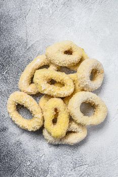 Frozen raw squid rings in breadcrumbs. White background. Top view