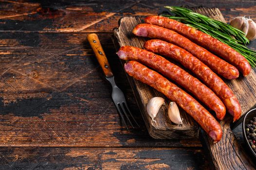 Hot Smoked sausages with addition of fresh aromatic herbs and spices. Dark wooden background. Top view. Copy space