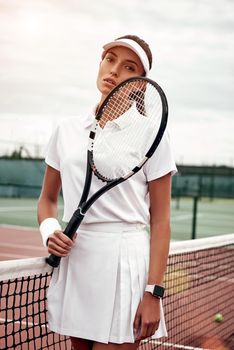 Young tennis player standing on a court and holding a racket.