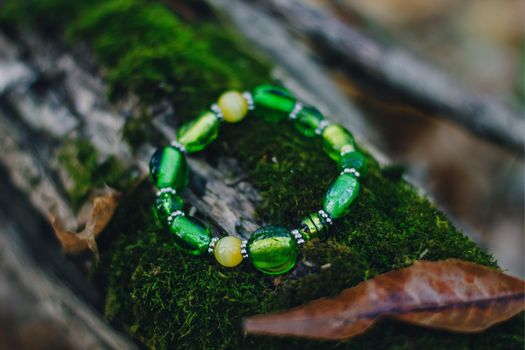 Bracelet handmade handcrafted do-it-yourself glass jewelry on natural wood forest background. Business idea, earning money for a hobby. Useful quarantined skills
