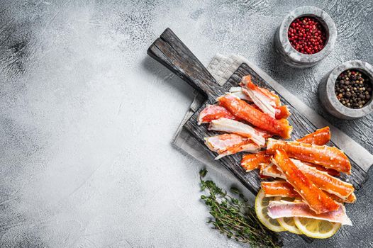 Cooked King Crab legs meat on a wooden board with herbs. White background. Top view. Copy space