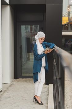 Modern Arabian muslim woman with tablet computer outdoors