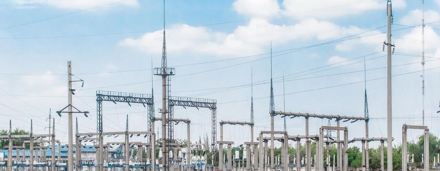 Electric substation of high-voltage power transmission lines electric towers against the background of blue sky