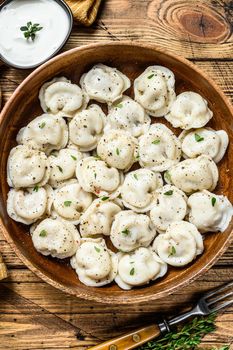 Homemade Russian Dumplings Pelmeni with beef and pork meat in a wooden bowl. wooden background. top view
