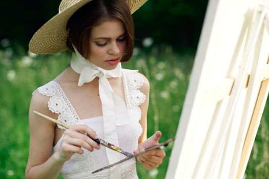 woman artist draws a picture on an easel outdoors. High quality photo