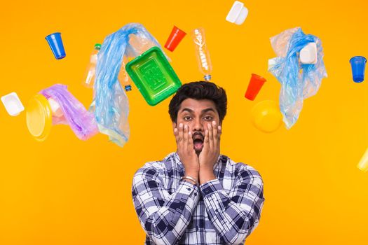 Environmental pollution, plastic recycling problem and ecology problem concept - Terrified Indian man on yellow background with trash