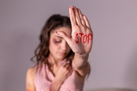 Domestic violence, protesting and people concept - brunette woman expressing denial with STOP on her hand on grey room