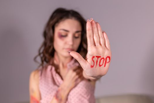 Domestic violence, protesting and people concept - brunette woman expressing denial with STOP on her hand on grey room