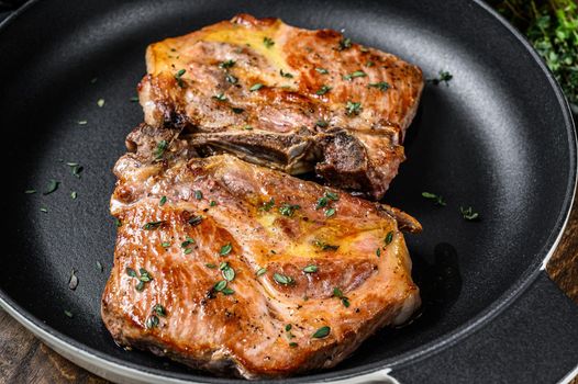 Fried pork loin steaks in a pan. Dark wooden background. Top view