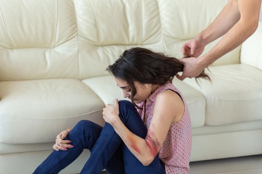 domestic violence, victim and abuse concept - cruel aggressive man grabbing woman lying on the floor