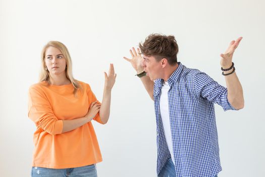 Young hipster guy shouts raising his hands up to his beloved girl showing by hands stop on a white background. Concept of bad relationships and family breakdown.