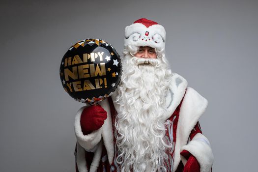 old santa claus holds a baloon in his hands and likes it