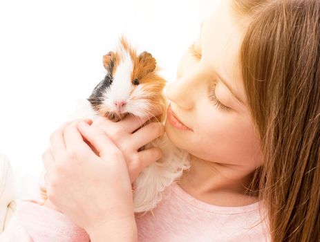 Charming little girl holding guinea pig near her cheek