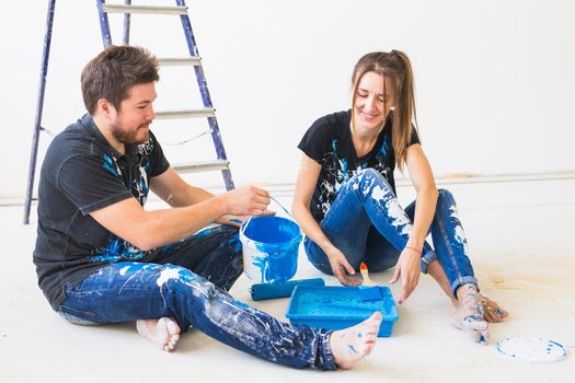 Repair, renovation and people concept - portrait of happy couple pour paint