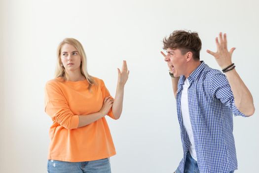 Young hipster guy shouts raising his hands up to his beloved girl showing by hands stop on a white background. Concept of bad relationships and family breakdown.