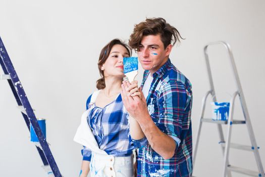 People, redecoration and relationship concept - Young funny couple doing renovation in new apartment