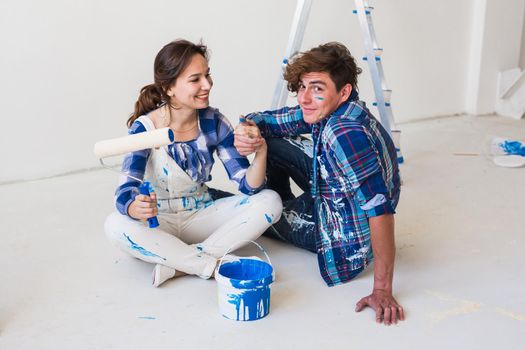 People and interiors concept - Young couple sitting on the white floor