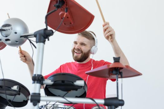 People, music and hobby concept - Tough man in red t-shirt and black sneakers playing electronic drum kit