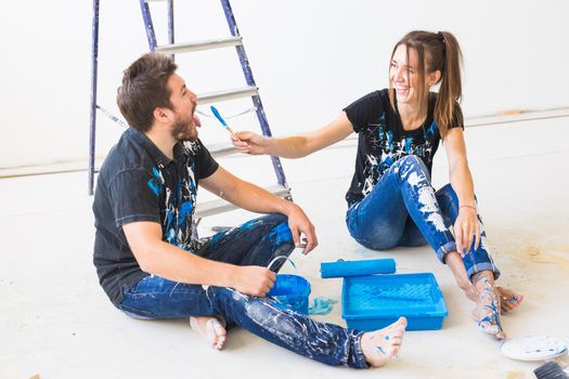 Renovation, repair and people concept - portrait of funny couple stained with paint over white background