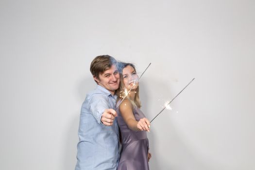 Fun, love and holiday concept - man and woman fooling around with sparklers
