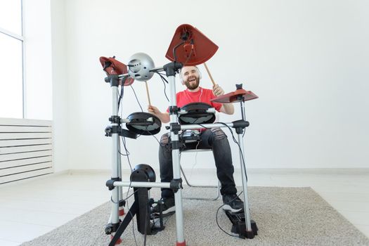 People, music and hobby concept - Tough man in red t-shirt and black sneakers playing electronic drum kit