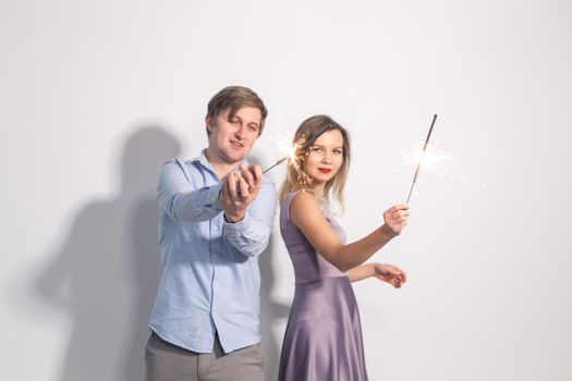 Fun, love and holiday concept - man and woman fooling around with sparklers