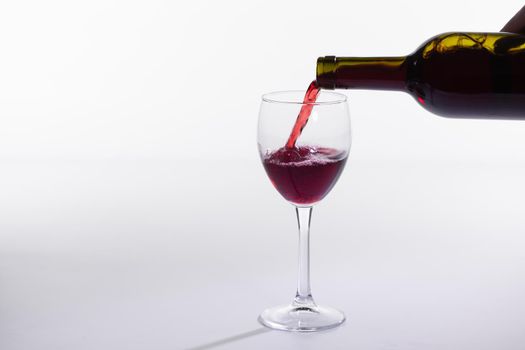 Red wine bottle pour glass on white background with copy space