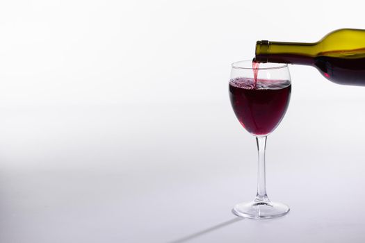 Red wine bottle pour glass on white background with copy space